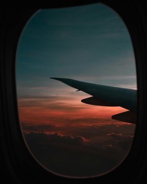 Leonardo Yip RN via Unsplash sunset out of and airplane window with the wing of the plane on the right of the window.