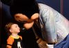 young child wearing a goofy shirt giving mickey mouse a kiss. ready for his first haricut at disney world