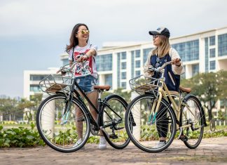 Explore & Restore: The Perfect Travel Trend for Busy Women two men laughing on bicycles with a city scape in the back. Waiting for the latest travel trend