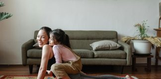 9 Mental Health Habits to Practice With Kids mom doing a yoga pose with child on top of her her. both are laughing, practicing good mental health habits.