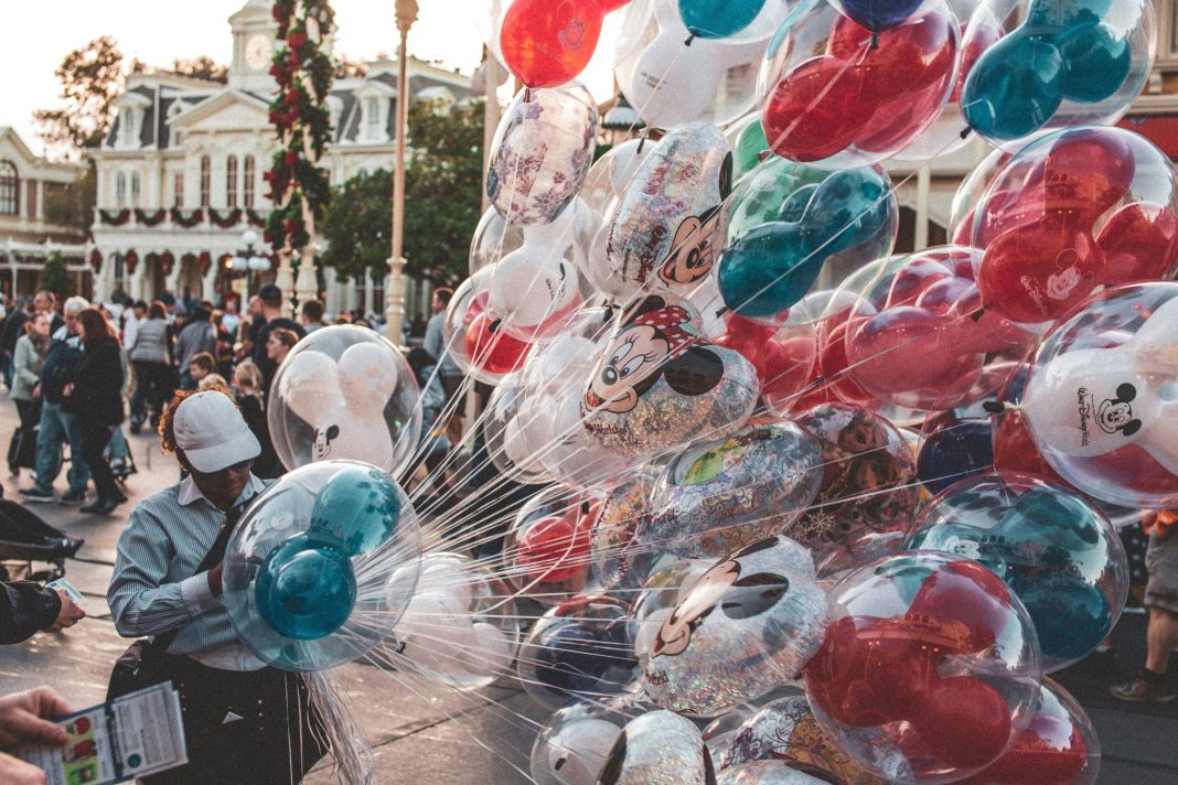 a cast member carrying many mickey mouse balloons. empty nester at disney