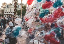 a cast member carrying many mickey mouse balloons. empty nester at disney