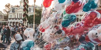 a cast member carrying many mickey mouse balloons. empty nester at disney