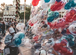 a cast member carrying many mickey mouse balloons. empty nester at disney