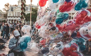 a cast member carrying many mickey mouse balloons. empty nester at disney