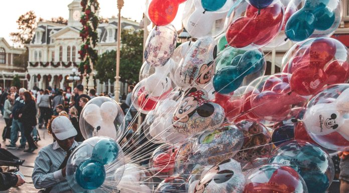 a cast member carrying many mickey mouse balloons. empty nester at disney