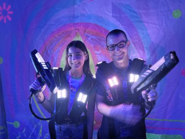 daughter and father holding laser guns for laser tag on a cruise ship, smiling at the camera