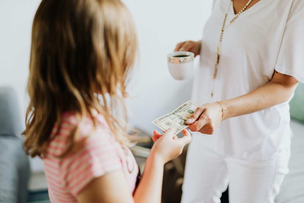 young girl receiving money from probably mom (out of frame) to invest in your child's future