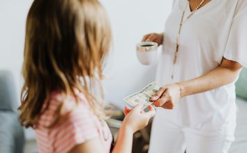 young girl receiving money from probably mom (out of frame) to invest in your child's future