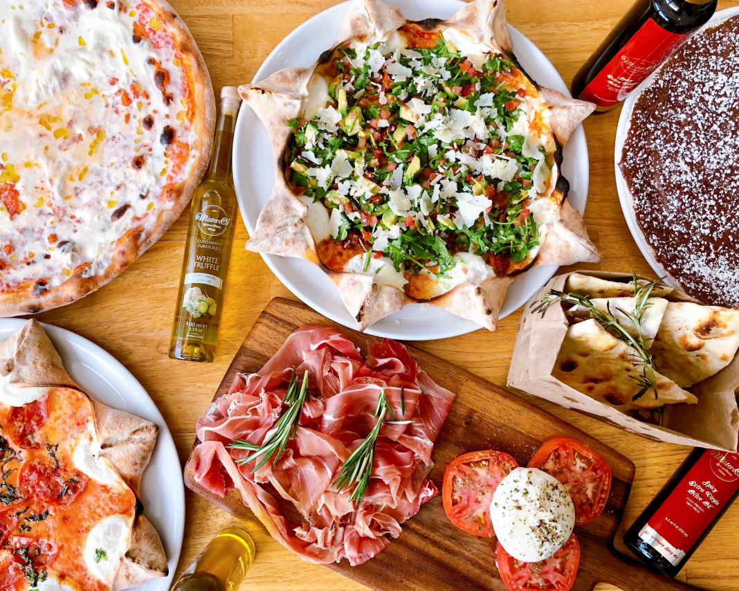 flat lay of food, mostly pizza and italian food, on an inviting table for restaurant for families with kids