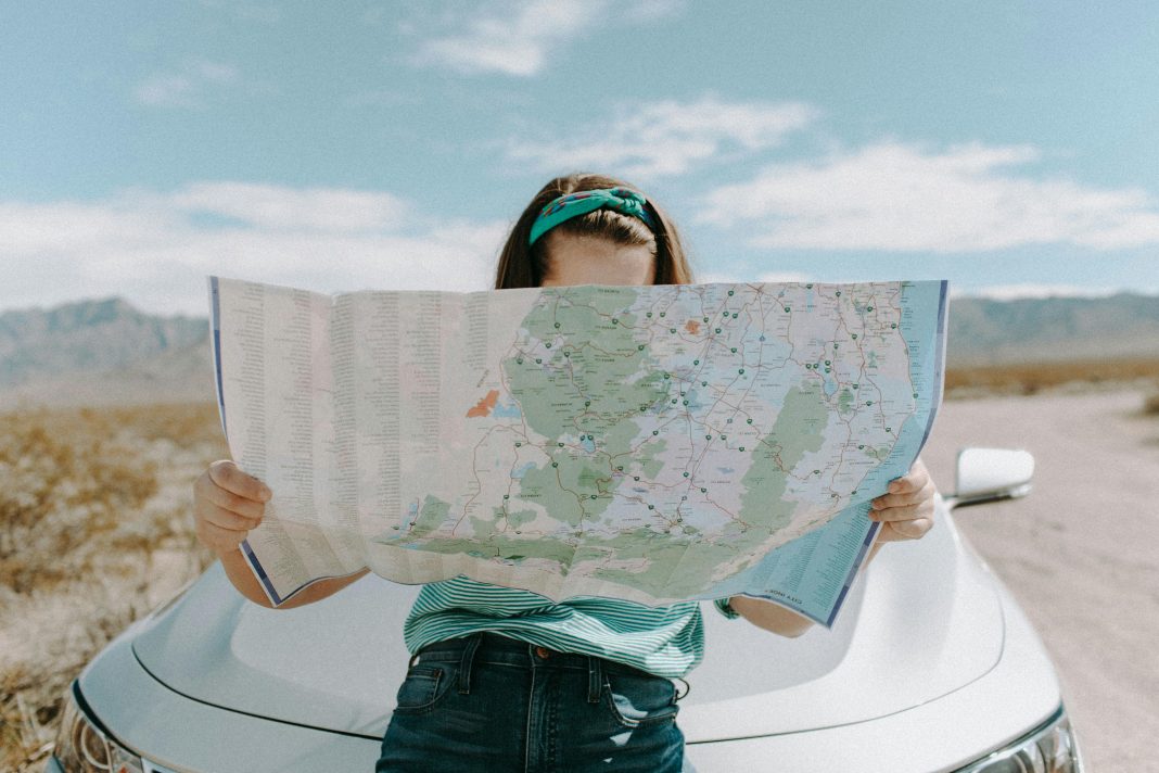 pexels-leah-newhouse-50725-3935702 woman reading a map (can't see her face) resting against her car trying to avoid mistakes while traveling