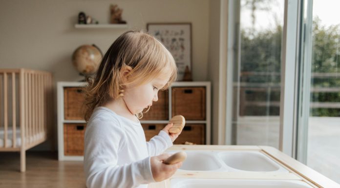 child in sensory play with smooth rocks and dry macaroni