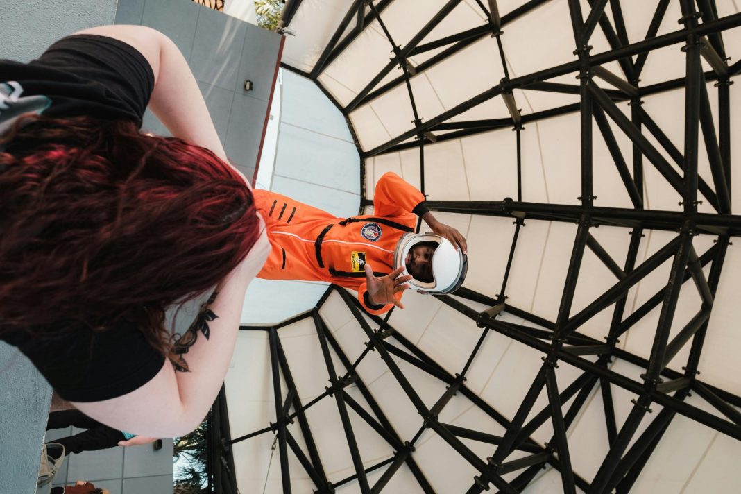 Man dressed in an astronaut suit posing for a photo indoors, showcasing one of the fun and educational indoor activities in Orlando for kids and families.