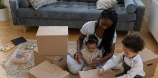 Mother sitting on the floor with her two young children, labeling cardboard boxes together for indoor activities in orlando.