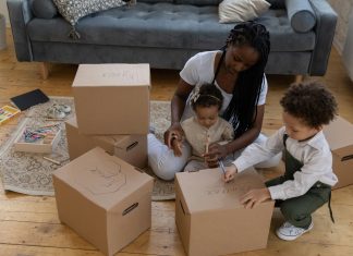 Indoor Activities in Orlando for Rainy or Blazing Hot Days (Low-Budget Edition) Mother sitting on the floor with her two young children, labeling cardboard boxes together for indoor activities in orlando.