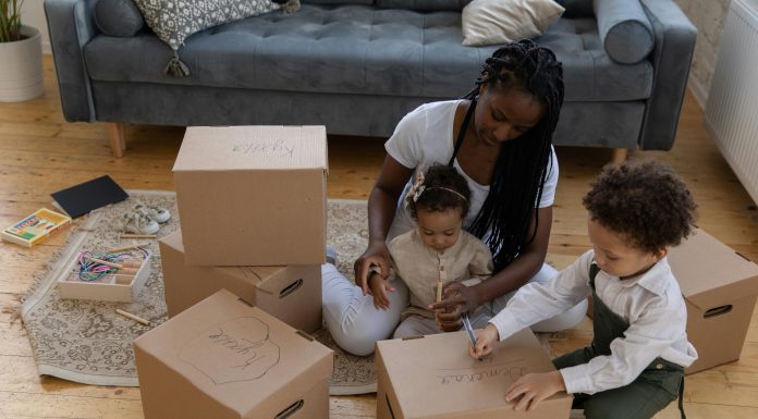 Indoor Activities in Orlando for Rainy or Blazing Hot Days (Low-Budget Edition) Mother sitting on the floor with her two young children, labeling cardboard boxes together for indoor activities in orlando.