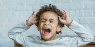 Surviving Toddler Tantrums: What Worked for Real Moms Young child mid-toddler tantrum with eyes closed, mouth open yelling, and hands raised to head in frustration.