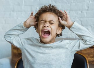 Surviving Toddler Tantrums: What Worked for Real Moms Young child mid-toddler tantrum with eyes closed, mouth open yelling, and hands raised to head in frustration.