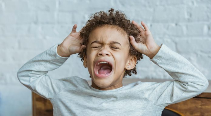 Surviving Toddler Tantrums: What Worked for Real Moms Young child mid-toddler tantrum with eyes closed, mouth open yelling, and hands raised to head in frustration.