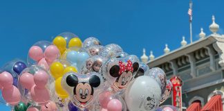 Colorful Disney balloons float in front of a Main Street, U.S.A. building at Magic Kingdom in Orlando, featuring Mickey, Minnie, and Frozen characters—perfect snapshot of what to expect (and what to pack for a family trip to Orlando).