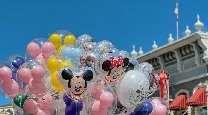 What to Pack for a Family Trip to Orlando (By a Mom Who Lives Here) Colorful Disney balloons float in front of a Main Street, U.S.A. building at Magic Kingdom in Orlando, featuring Mickey, Minnie, and Frozen characters—perfect snapshot of what to expect (and what to pack for a family trip to Orlando).