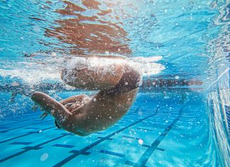 Water Safety and a Beach Day: Smart Tips for a Fun, Safe Summer Swimmer performing an underwater flip turn in a pool, highlighting athletic skill and promoting water safety awareness.