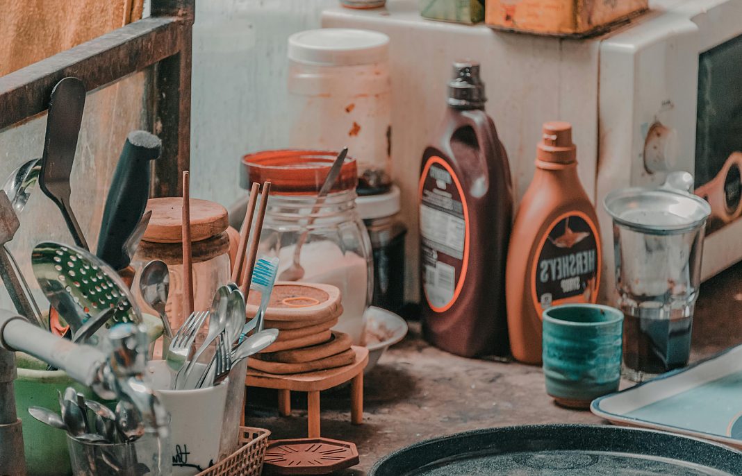Kitchen counter crowded with utensils, jars, and sauce bottles illustrating the mental load of clutter during busy summer days