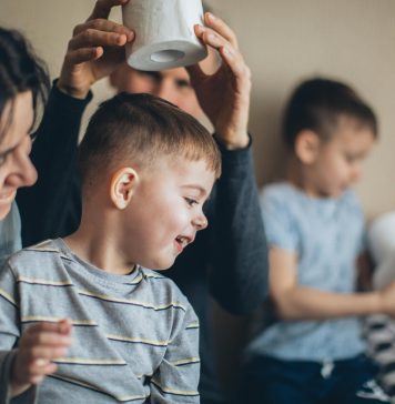 Mother and children sitting together at a table, smiling and talking, highlighting family routines and public health awareness.