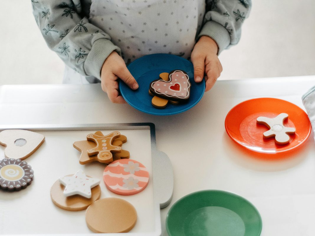pexels-fotios-photos-10241142 Child’s hands holding a plastic plate of toy cookies at a cookies for kids cancer fundraiser.