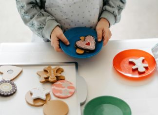 Child’s hands holding a plastic plate of toy cookies at a cookies for kids cancer fundraiser.
