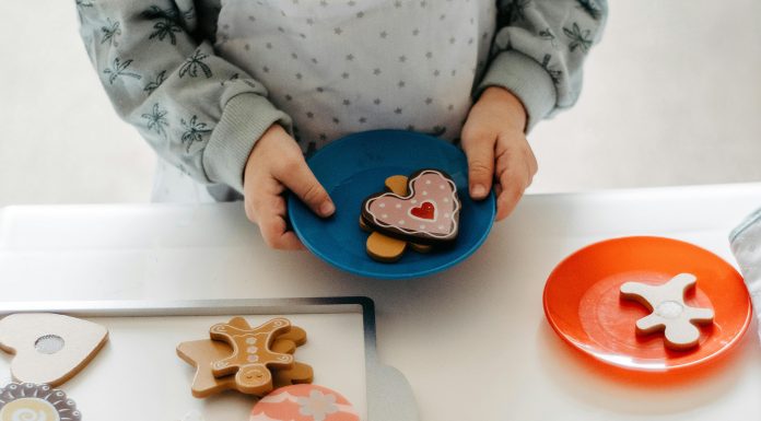 Cookies for Kids Cancer: Empowering Communities to Fund Pediatric Research Child’s hands holding a plastic plate of toy cookies at a cookies for kids cancer fundraiser.