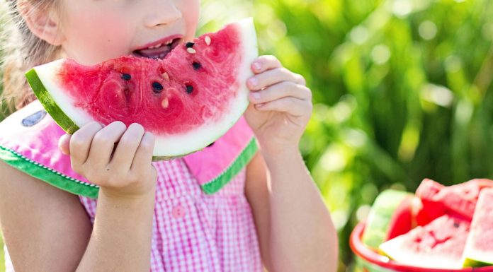 Summer Break Help: The Child-Free Auntie’s Guide to Showing Up girl eating sliced watermelon fruit beside table during summer break